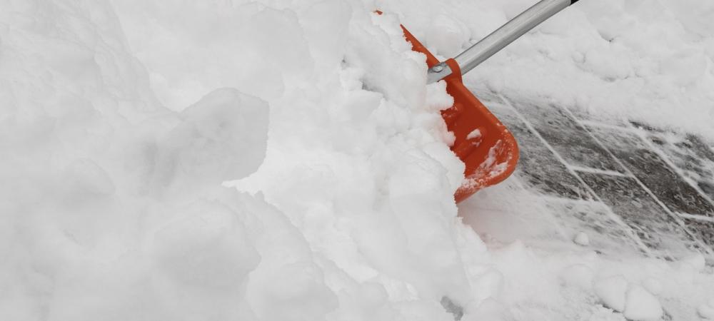 Someone shoveling snow with an orange shovel